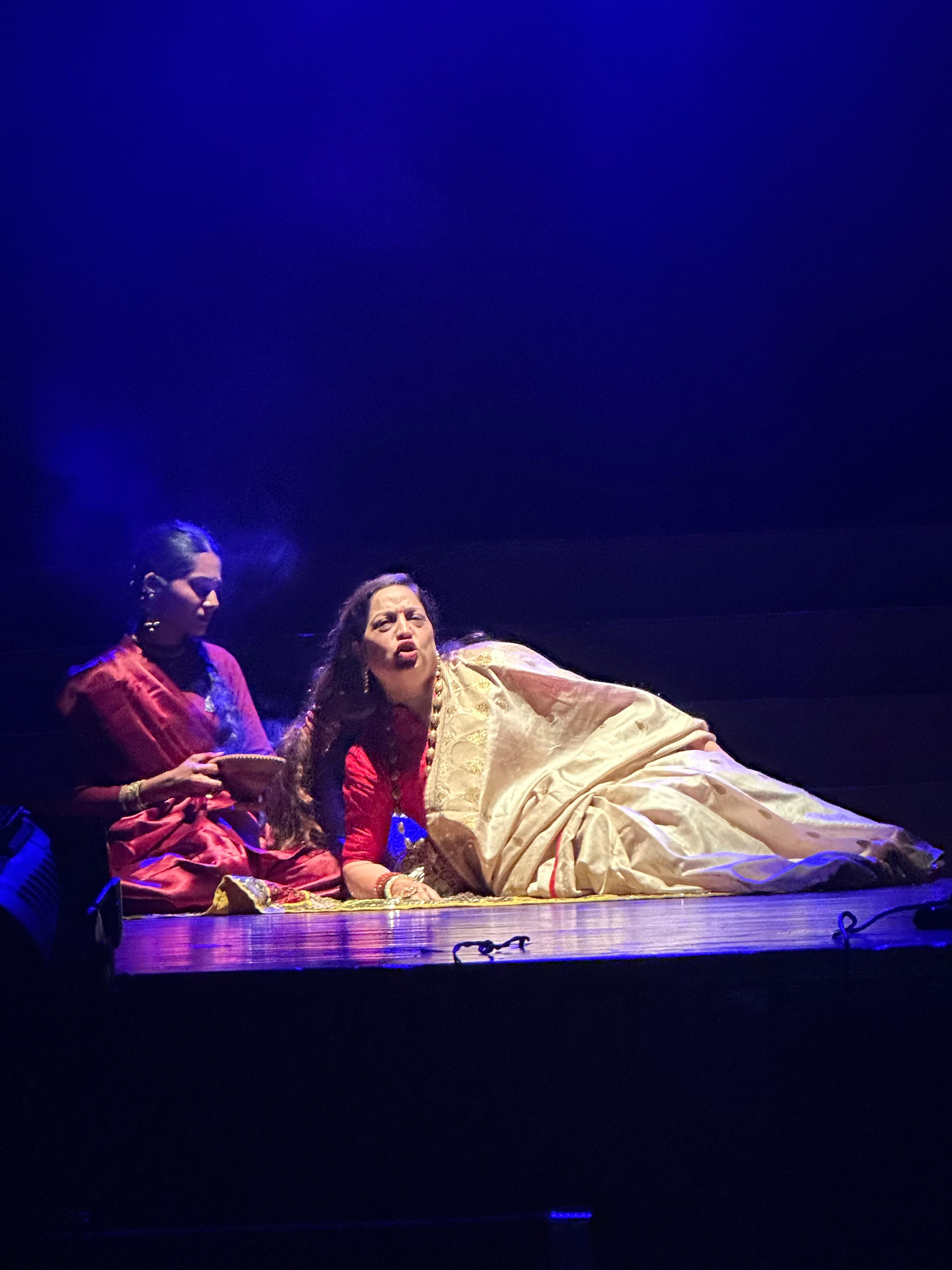 Two performers in a dramatic scene under blue light