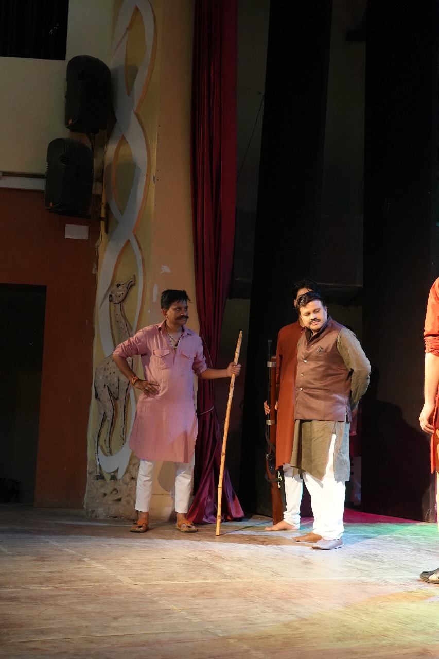 Actors holding staffs near the stage curtain