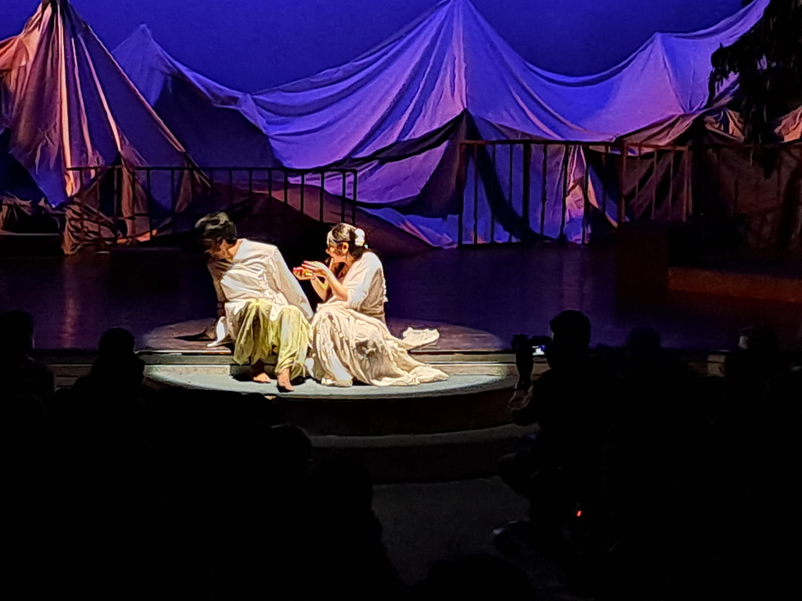 Two actors seated together under a spotlight